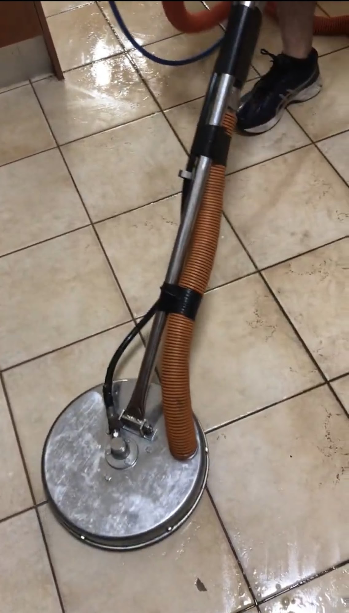 Rotary tile cleaning tool at work on ceramic floor