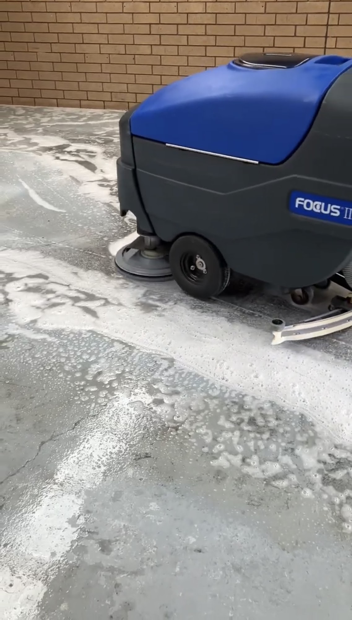Industrial floor scrubber cleaning a commercial forecourt